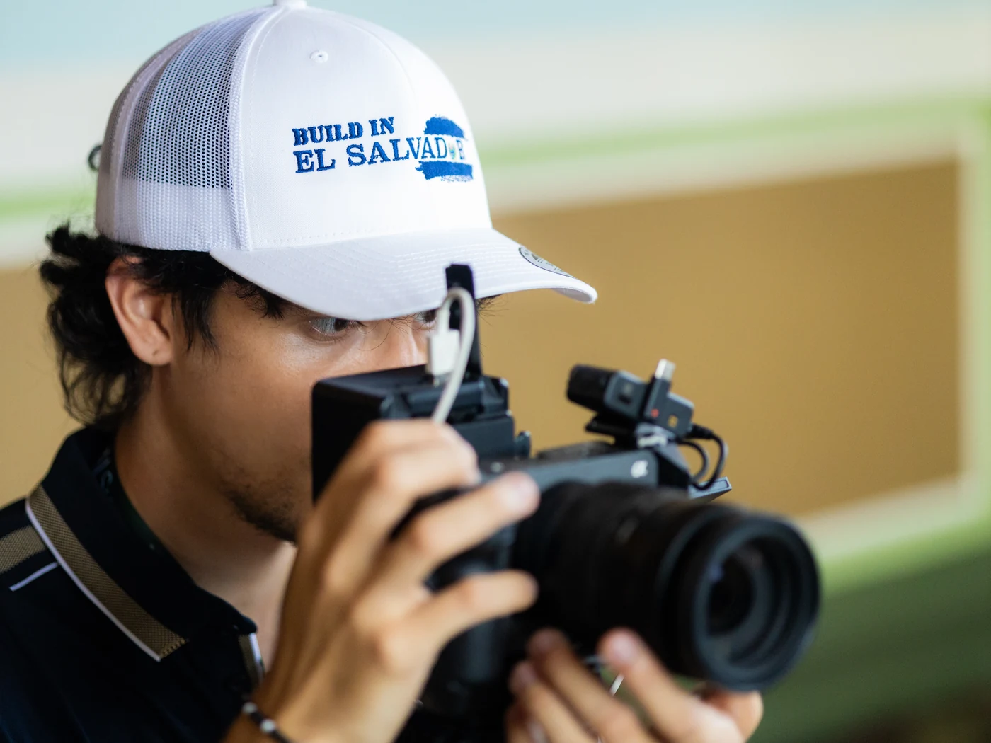 A BIES videographer in a Build in El Salvador cap filming with a camera